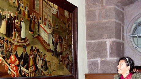 FFM_Wozu_wir_uns_bekennen Fotoaufnahme der Führung „Bekenntnis – wozu wir uns bekennen“ in der Bad Windsheimer Spitalkirche. An einer Wand hängt ein Gemälde im Holzrahmen. Davor stehen zwei Jugendliche, die es betrachten. Die Wand rechts daneben besteht aus Sandsteinquadern.