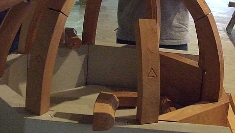 FFM_Gewoelbe Fotoaufnahme der Führung „Knotenschnur und Zirkelschlag“ in der Spitalkirche. Eine Besuchergruppe baut aus Holzklötzen das Modell eines Gewölbes. Das Modell ist etwa zur Hälfte fertig, in der Mitte liegen noch einige Bauteile.